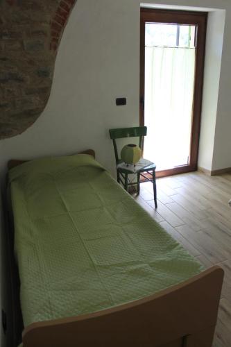 a bedroom with a green bed and a chair and a window at Casa Andreini in Mombarcaro