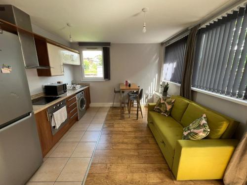 a living room with a green couch and a kitchen at London Modern Flat near transports in London