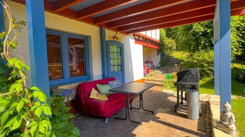 a patio with a red chair and a table and a stove at Wie im Himmel in Hatzfeld