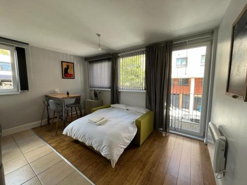1 dormitorio con cama, mesa y ventanas en London Modern Flat near transports en Londres