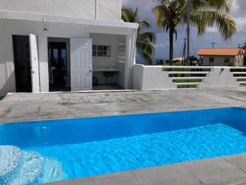 a blue swimming pool in front of a white house at The White House in Calliaqua