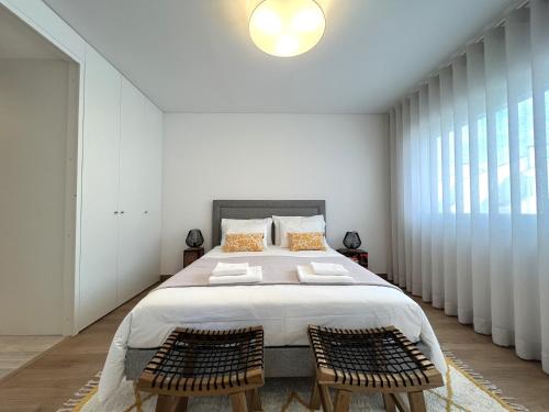 a bedroom with a large bed with two chairs at Mar-à-Vista Apartment Nazaré in Nazaré
