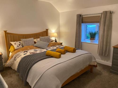 a bedroom with a bed with yellow pillows and a window at Idillic Two bed country cottage in Kirkby Thore
