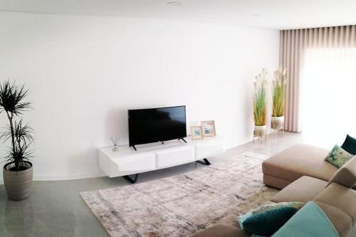 ein Wohnzimmer mit einem Flachbild-TV an einer weißen Wand in der Unterkunft Alojamento familia Carvalhais in Ponte de Vagos