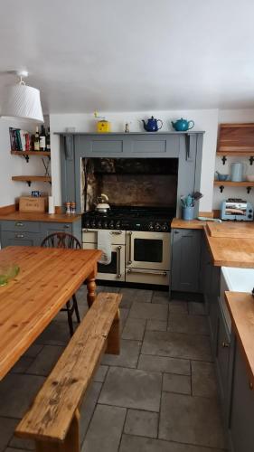 a kitchen with a stove and a wooden table at Blue Ensign Cottage in Weymouth