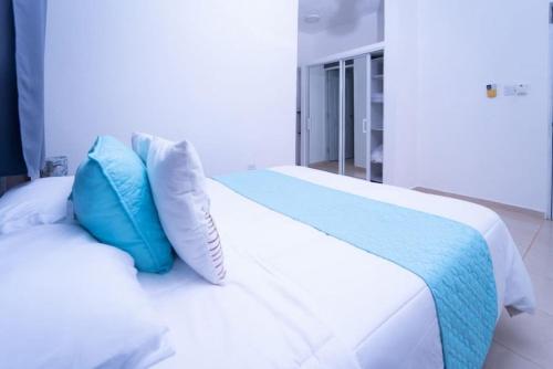 Una cama blanca con almohadas azules encima. en Cozy apartment in Samana with Jacuzzi, en Santa Bárbara de Samaná