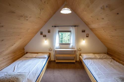 two beds in a attic room with a window at Domek w górach SmoLenisko in Nowy Targ