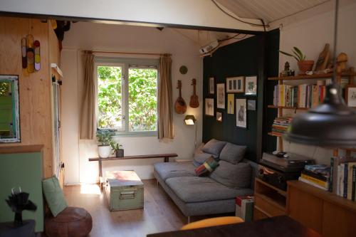 a living room with a couch and a window at Knus boshuisje onder de eiken in Ermelo