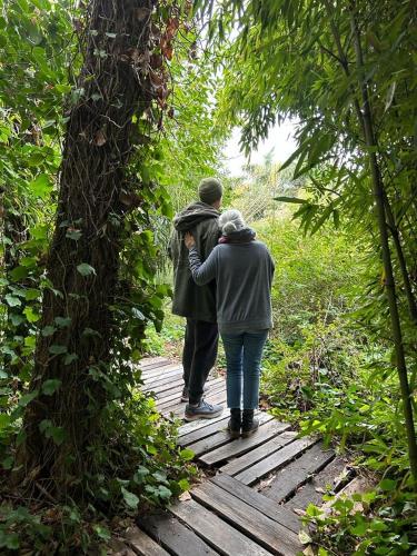 two people walking on a wooden path in the woods at SUITE DEL BOSQUE Desayuno Domingos check out 17hs in Tigre