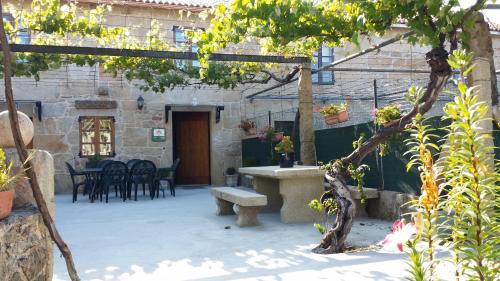 a patio with a bench and a table and chairs at Casa Rural Vella da Rivera in O Sisto