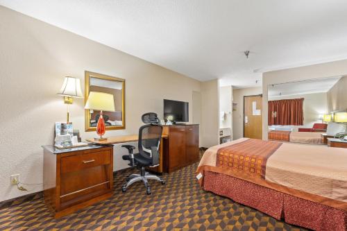 a hotel room with a bed and a desk with a computer at Geneva Motel Inn in Saint Charles