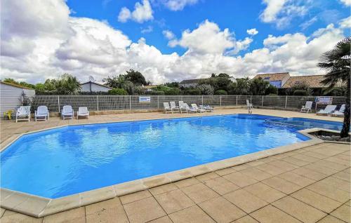 une grande piscine bleue avec des chaises sur la terrasse dans l'établissement Chalet spacieux à 8 km de la mer, à LʼAiguillon-sur-Vie