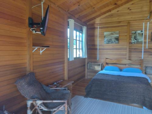 a bedroom with a bed in a wooden cabin at Estancia Aguas Brancas in Urubici