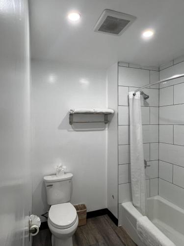 La salle de bains blanche est pourvue d'une douche et de toilettes. dans l'établissement Sunshine Motel, à Long Beach