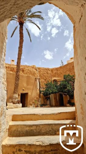 a building with a palm tree and some stairs at Touring Club MARHALA MATMATA in Matmata