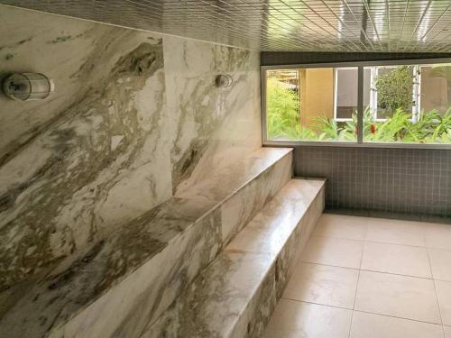 a bathroom with a large stone wall with a window at Apartamento com piscina aquecida e churrasqueira in Ubatuba