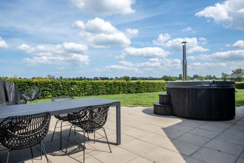 eine Terrasse mit einem Tisch und Stühlen sowie einem Whirlpool in der Unterkunft Fuglhus - hyggelig ferie på landet in Rødekro