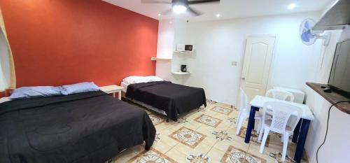 a bedroom with two beds and a red wall at Villa Trinidad in La Ceiba