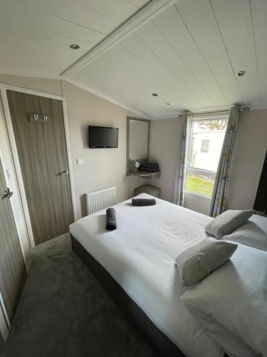 a bedroom with a large white bed and a window at Sea Breeze in Perranporth