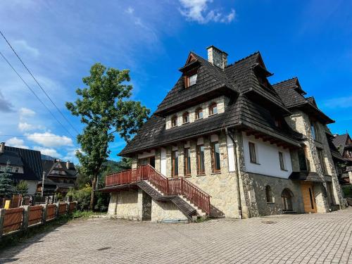 an old stone house with a black roof and stairs at Dom Górski 878 mnpm in Zakopane