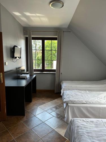 um quarto com 2 camas, uma secretária e uma janela em Pokoje Komfort em Szypliszki