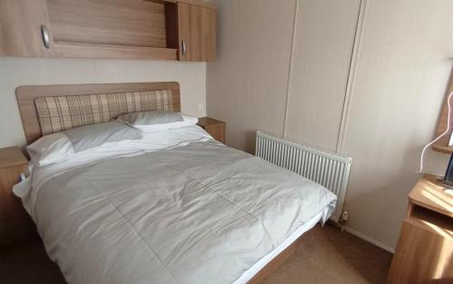a bedroom with a white bed with a wooden headboard at Bordeaux - Church Farm in Pagham