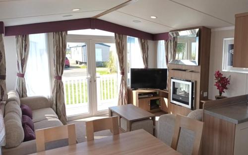 a living room with a couch and a television at Bordeaux, Home From Home, Church Farm in Pagham