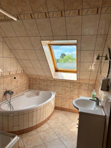 baño con bañera, lavabo y ventana en Pokoje Komfort, en Szypliszki