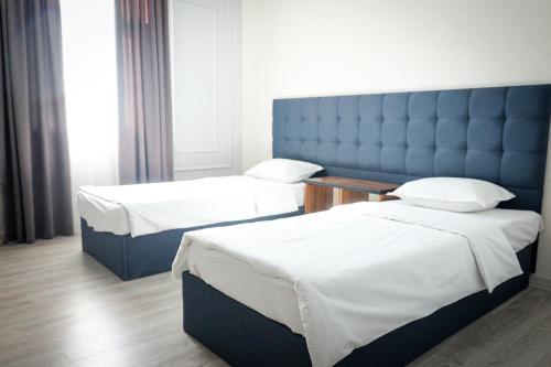 a hotel room with two beds and a blue headboard at Hotel Borjomi in Shymkent