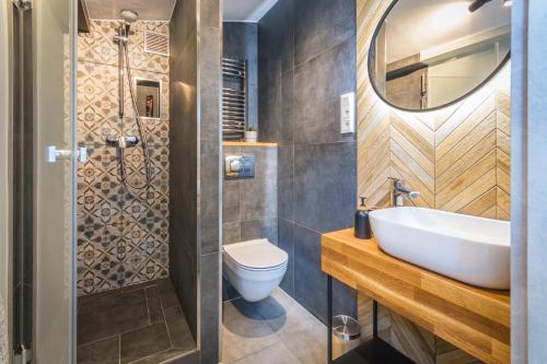 La salle de bains est pourvue d'un lavabo, de toilettes et d'un miroir. dans l'établissement Apartamenty Fabrykanta Nowe Centrum Łodzi, à Łódź