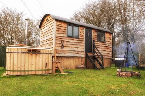 a small wooden house with a tub in a yard at Homestead Hut 