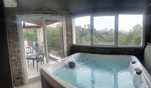 een bad in een kamer met 2 ramen bij Villa de charme piscine et jacuzzi 190 m2 in Mouans-Sartoux