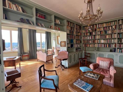 een woonkamer met boekenplanken en een kroonluchter bij L'attico del 1600 in centro in Perugia