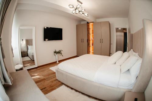 a white bedroom with a large bed and a mirror at Cosy apartment Bucovina in Suceava