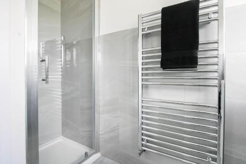 uma casa de banho com um chuveiro e uma toalha preta em Stunning 4 bedroom home near cotswolds and Stratford upon avon em Tredington