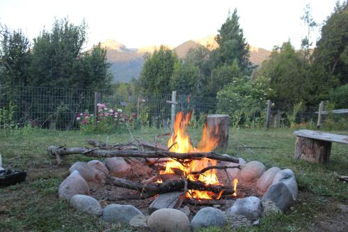 a fire in a field with logs and a bench at Huerta de los Andes - Bed and Breakfast in Villa La Angostura
