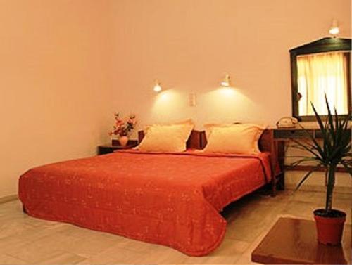 a bedroom with a red bed with a desk and a window at Calypso Hotel Apartments in Kato Daratso