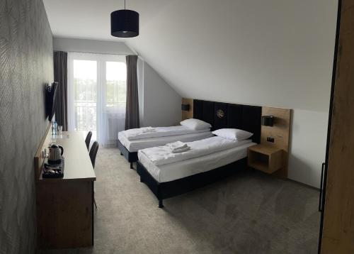 a hotel room with two beds and a desk at Karczma u Jana in Kuczów