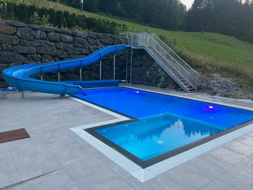 a blue pool with a slide in a stone wall at Hotel Sonnenalm Stuhleck in Spital am Semmering
