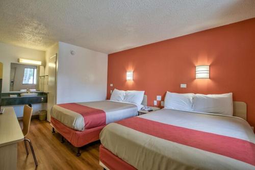a hotel room with two beds with red walls at Loyalty Inn Tallahassee in Tallahassee