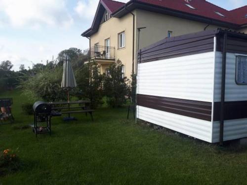a house with a white and black garage next to a yard at Domek Holenderski in Mielno