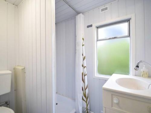 a white bathroom with a sink and a window at Domek Holenderski in Mielno