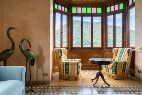 een woonkamer met stoelen en een tafel en ramen bij Villa Cecilia - pieds dans l'eau in Sulzano