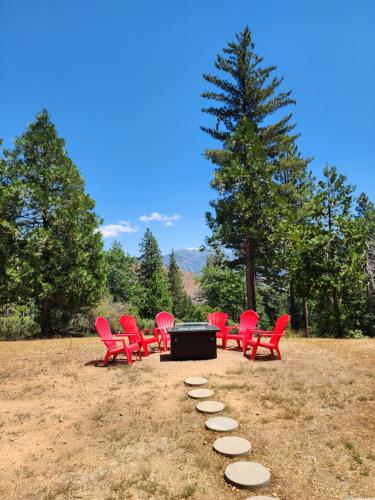 a group of red chairs and a table in a field at Moonrise Lodge - A Large Vacation Home in Mariposa in Mariposa