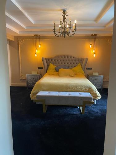 een slaapkamer met een bed met gele kussens en een kroonluchter bij Villa de charme piscine et jacuzzi 190 m2 in Mouans-Sartoux