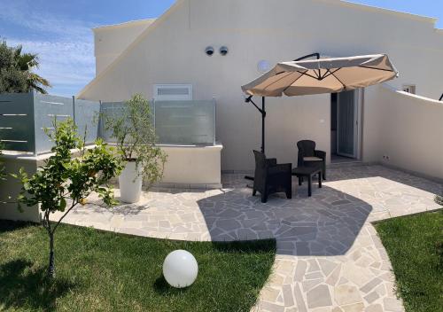 a patio with a table and chairs and an umbrella at Tenuta Verdolivo in Ostuni