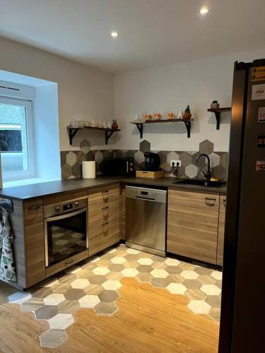 une cuisine avec des appareils en acier inoxydable et des armoires en bois dans l'établissement Un doux refuge, à LʼHospitalet-près-lʼAndorre