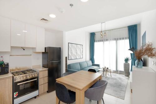 a kitchen and living room with a wooden table and chairs at Nice 1Bedroom - UNA Townsquare in Dubai
