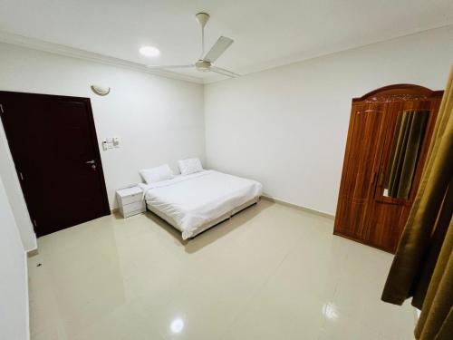 a white room with a bed and a wooden cabinet at المزار للشقق الفندقية 1 in Salalah