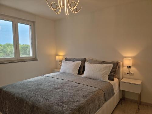 a bedroom with a bed with two tables and a chandelier at Luxury Apartment Umag in Umag